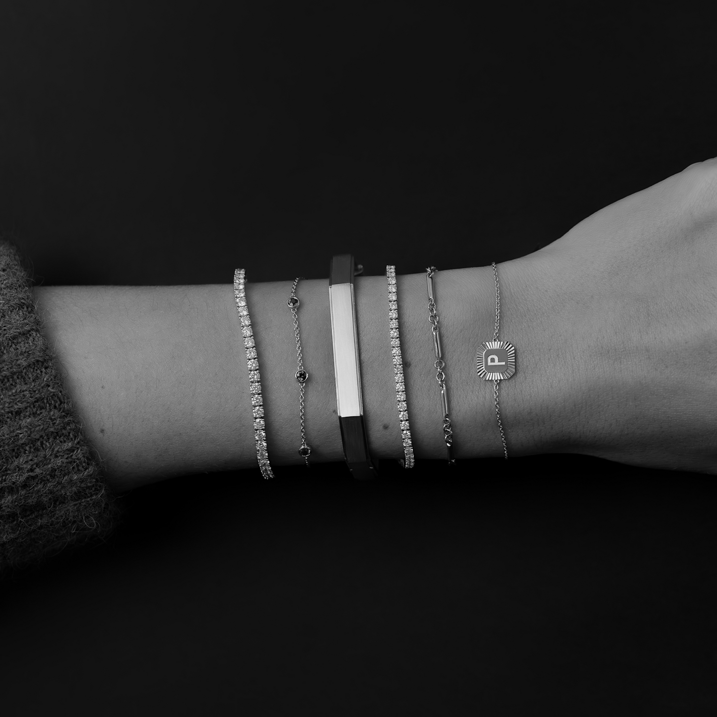 Close-up of a wrist wearing multiple bracelets on a dark background