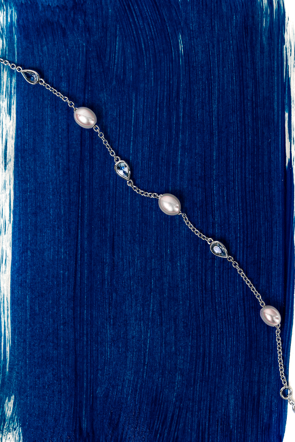 Necklace with pearls on a blue and white brushstroke background