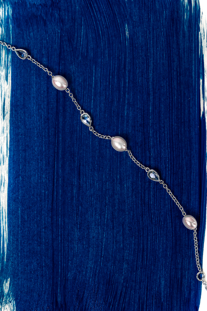 Necklace with pearls on a blue and white brushstroke background