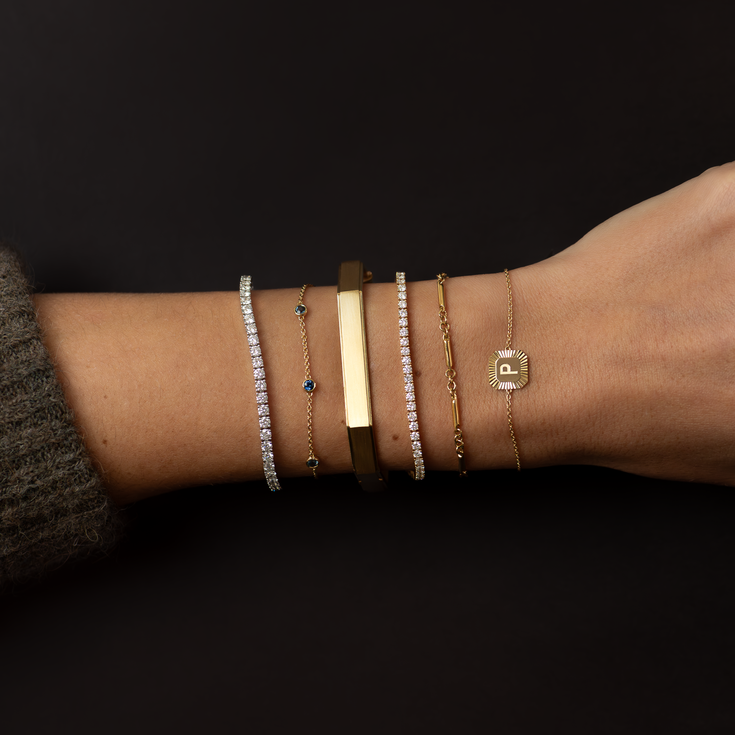 Close-up of a wrist wearing multiple bracelets on a dark background
